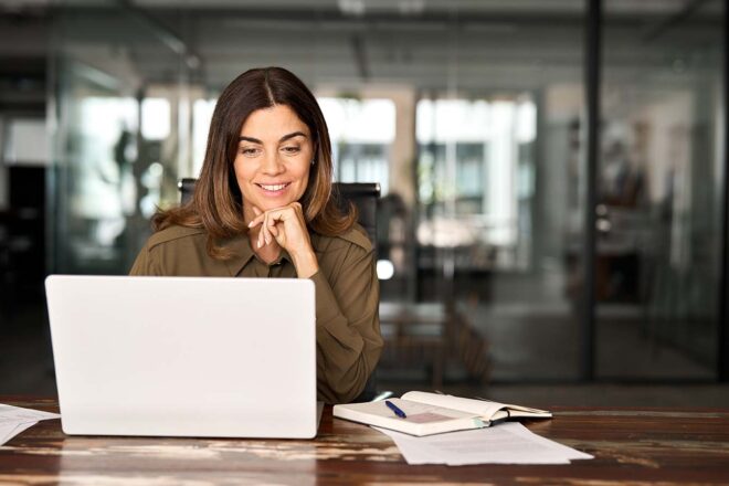 Themenbild neuer DATEV-Marktplatzpartner: Frau am Schreibtisch schaut auf den Bildschirm ihres PCs, neben ihr liegen Unterlagen